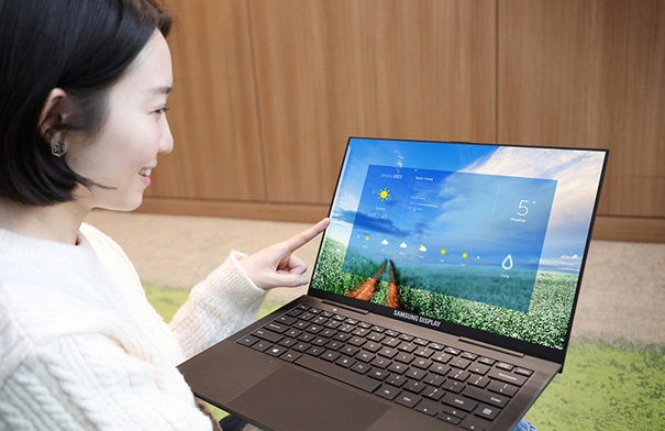 삼성디스플레이 직원이 터치 일체형 OLED가 적용된 노트북 컨셉 제품을 손으로 작동시키고 있는 모습
